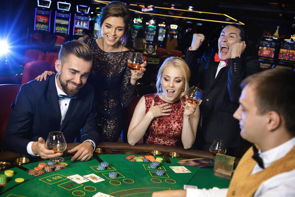 Happy rich people celebrating successful poker game in the casino