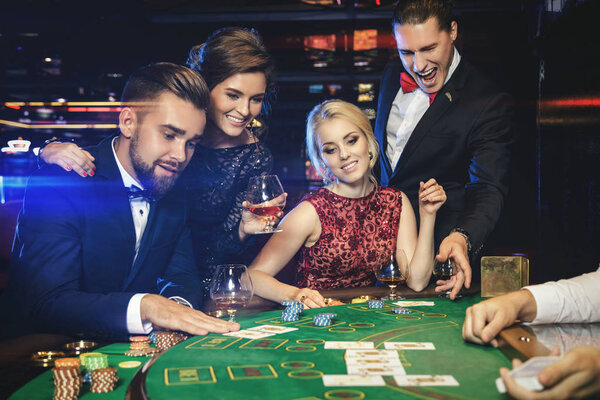 Group of young rich people playing poker in the casino