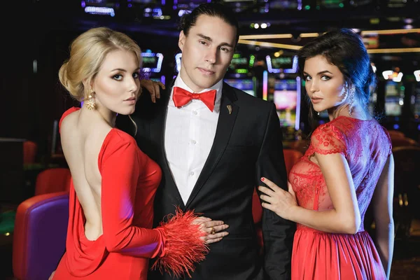 Confident Young Man Two Beautiful Women Wearing Red Cocktail Dresses — Stock Photo, Image