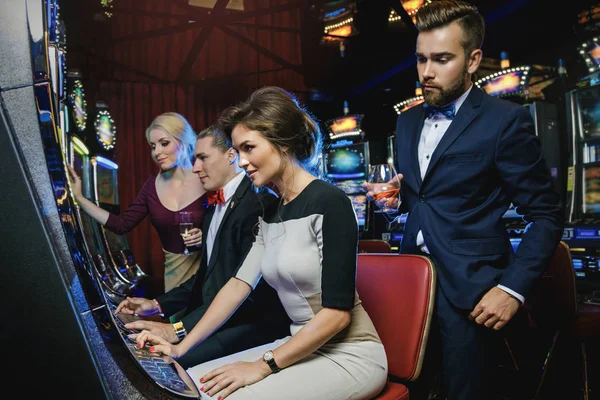 カジノでスロット マシンをプレイする友人のグループ — ストック写真