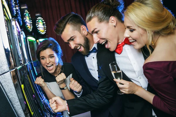 カジノでスロット マシンをプレイする友人のグループ — ストック写真