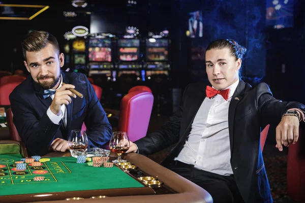 Two rich and handsome guys drinking cognac and playing roulette in the casino