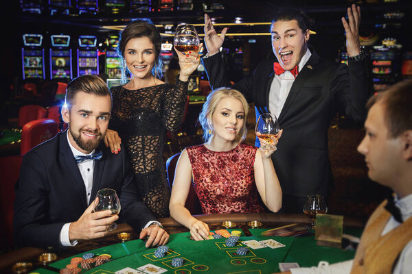 Happy rich people celebrating successful poker game in the casino