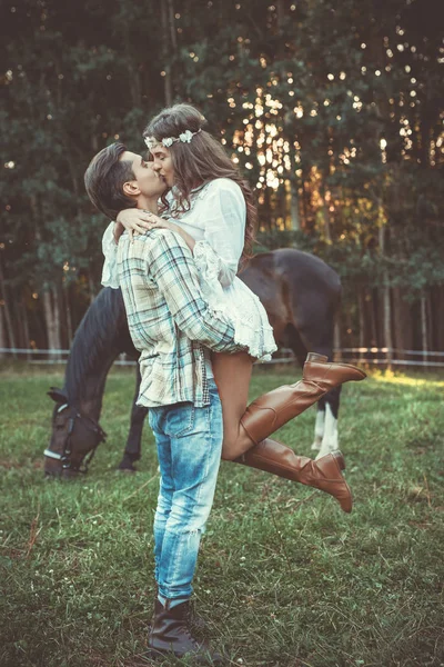 Genç ve kucaklama bir at ile çayır üzerinde mutlu çift