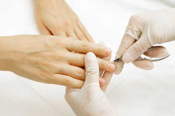 Manicure master during work. Close up of hands with a nipper