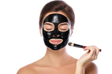 Güzel kadın arındırıcı siyah maske yüzünde beyaz arka plan üzerinde uyguluyor