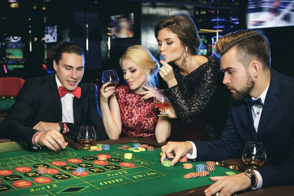 Young, well dressed and rich people playing roulette in the casino