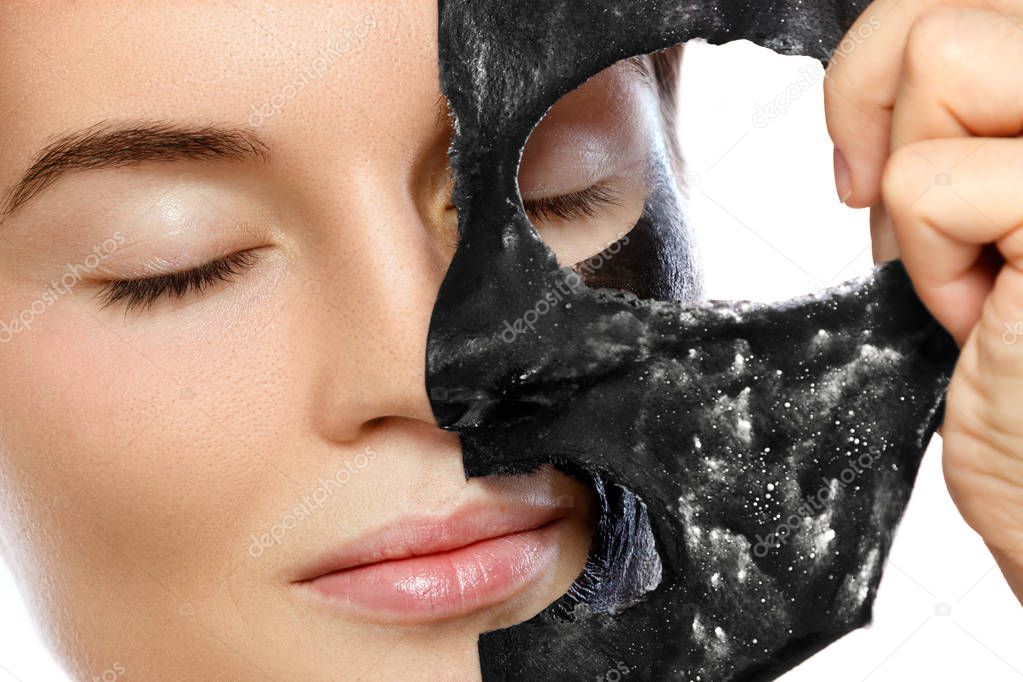 Beautiful woman is removing purifying mask from her face over white background