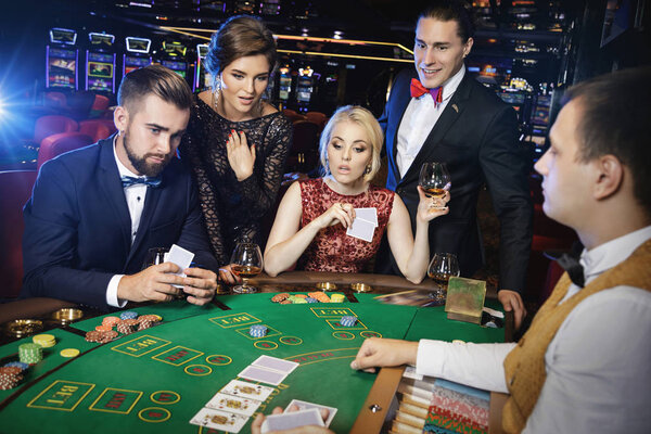 Group of young rich people is playing poker in the casino