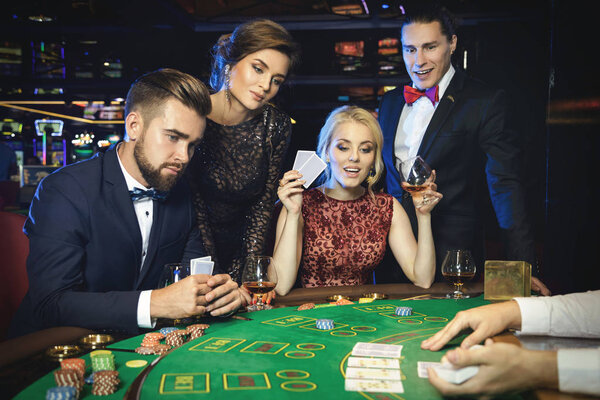 Group of young rich people is playing poker in the casino