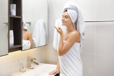 Gözlerinin altında nemlendirici ve anti-aging krem kullanan kadın