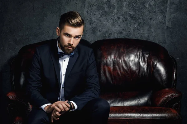 Handsome man sitting on the leather sofa — Stock Photo, Image