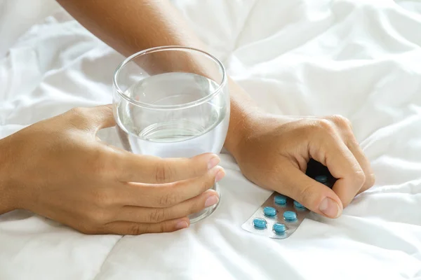 Frauenhände mit einem Glas Wasser und Tabletten — Stockfoto