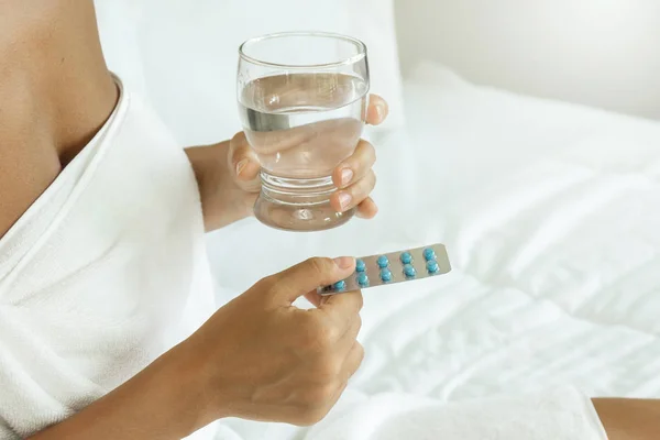 Frauenhände mit einem Glas Wasser und Tabletten — Stockfoto