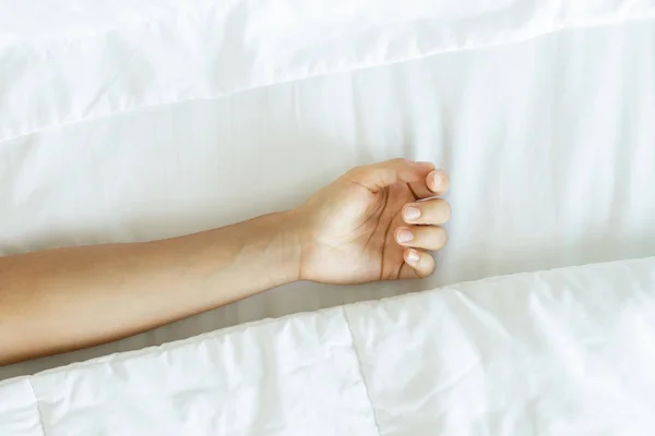 Lonely female hand on the soft bed linen — Stock Photo, Image