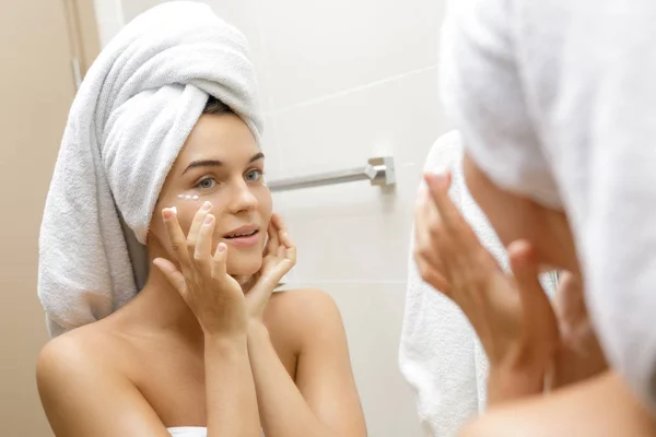 Mujer usando crema hidratante y antienvejecimiento bajo sus ojos — Foto de Stock