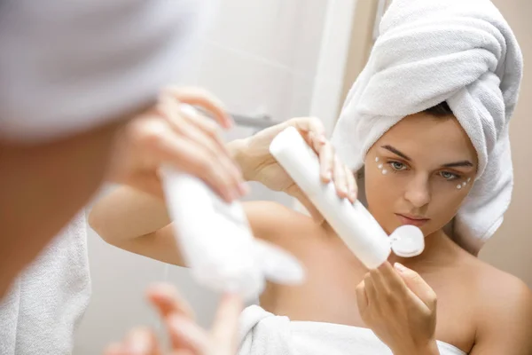 Mujer usando crema hidratante y antienvejecimiento bajo sus ojos — Foto de Stock