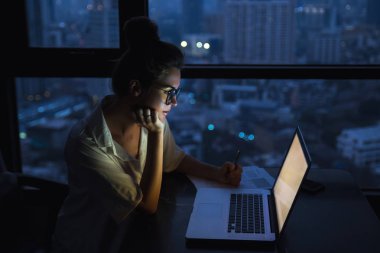 Kadın gece evde dizüstü bilgisayar ile çalışıyor.