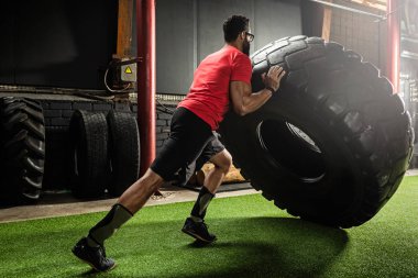 Güçlü sporcu lastik çevirme egzersizi yapıyor