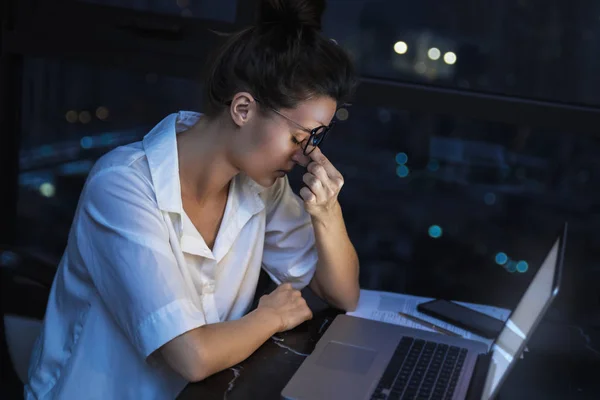 Vrouw werkt 's nachts met laptop thuis. — Stockfoto