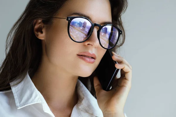 Young businesswoman in eyeglasses talking by smartphone — Stock Photo, Image