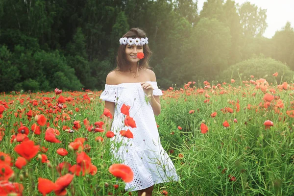 Mulher bonita no campo com um monte de flores de papoula — Fotografia de Stock