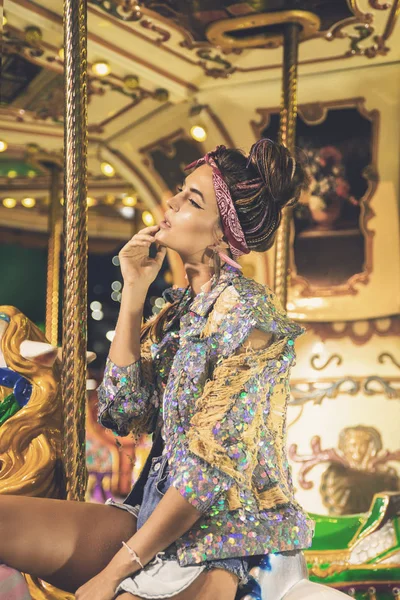 Stylish woman wearing sparkling jacket on the carousel — Stock Photo, Image