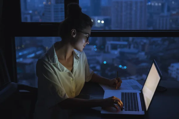 Vrouw werkt 's nachts met laptop thuis. — Stockfoto