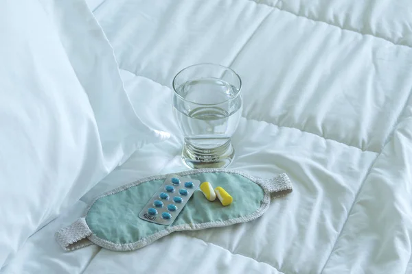 Blister pack of sleeping pills, blindfold and glass of water