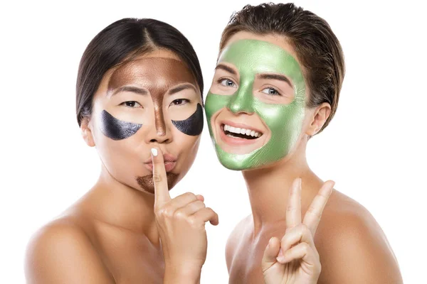 Two beautiful girls with colorful peel-off masks on their faces — Stock Photo, Image