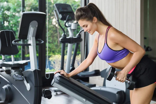 Vrouw tijdens de back workout. Een hand halter rij. — Stockfoto