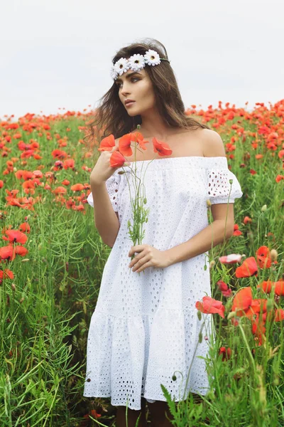 Hermosa mujer en el campo con un montón de flores de amapola — Foto de Stock