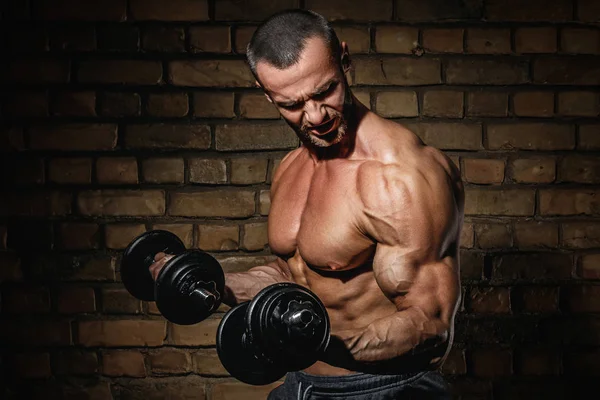 Fisiculturista fazendo exercícios para bíceps com halteres — Fotografia de Stock