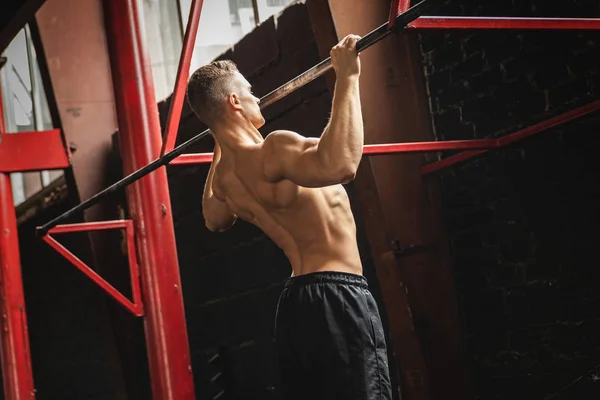 Homem forte fazendo exercício puxar para cima no ginásio — Fotografia de Stock