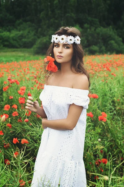 Hermosa mujer en el campo con un montón de flores de amapola — Foto de Stock