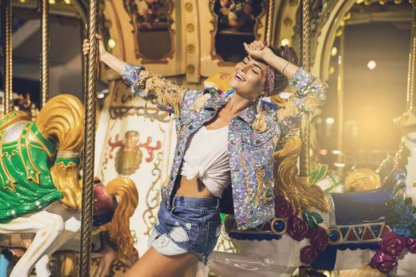 Stylish woman wearing sparkling jacket on the carousel — Stock Photo, Image