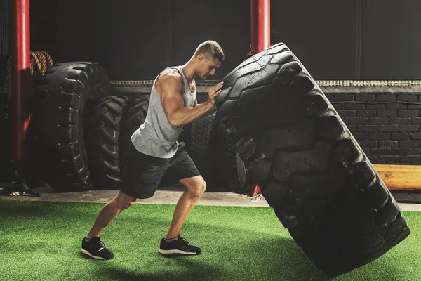 Starker Sportler bei einer Reifenflip-Übung — Stockfoto