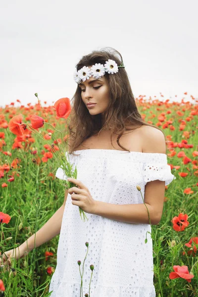 Hermosa mujer en el campo con un montón de flores de amapola — Foto de Stock