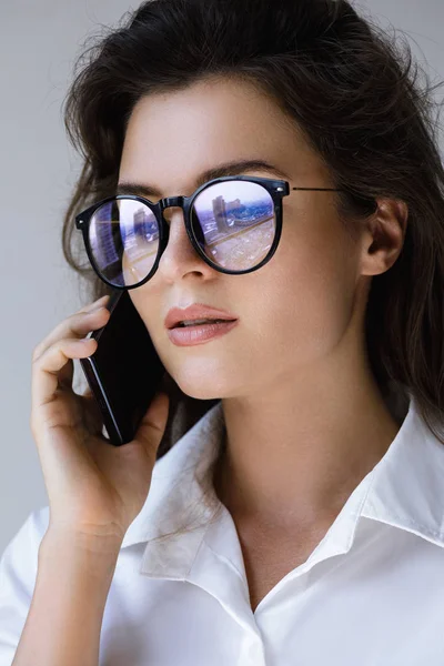 Young businesswoman in eyeglasses talking by smartphone — Stock Photo, Image
