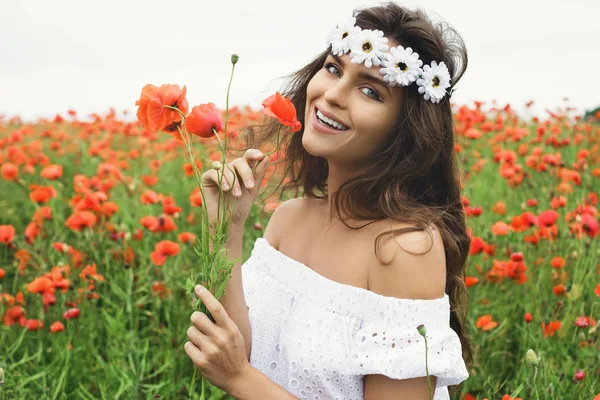 Hermosa mujer en el campo con un montón de flores de amapola — Foto de Stock