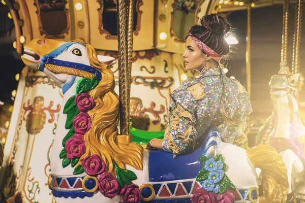 Stylish woman wearing sparkling jacket on the carousel — Stock Photo, Image