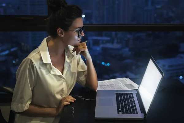 Vrouw werkt 's nachts met laptop thuis. — Stockfoto