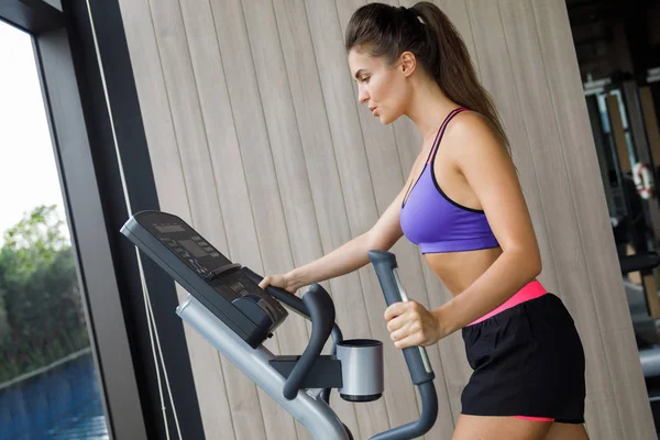 Sporty is woman using elliptical trainer — Stock Photo, Image