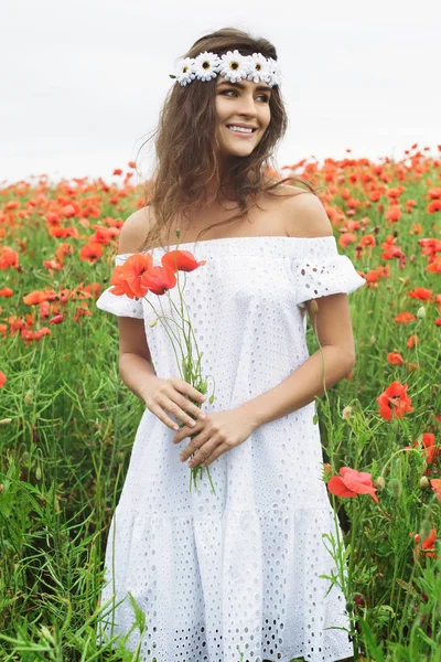 Hermosa mujer en el campo con un montón de flores de amapola — Foto de Stock