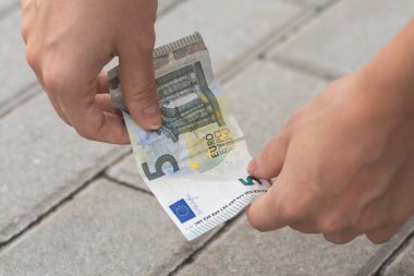 Kadın yerden beş euro banknot topluyor
