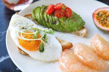 Kahvaltıda kızarmış yumurta avokado ve meyve ile Tost