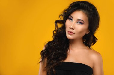 Güzel bir kıvırcık saçlı asyalı kadın ve sarı ba makyaj