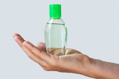 Hand with a small bottle of hand sanitizer  clipart