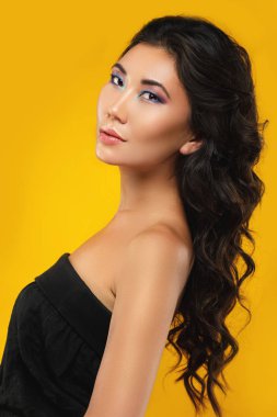 Güzel bir kıvırcık saçlı asyalı kadın ve sarı ba makyaj