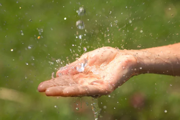 Mani femminili bagnate e spruzzi d'acqua limpidi — Foto Stock